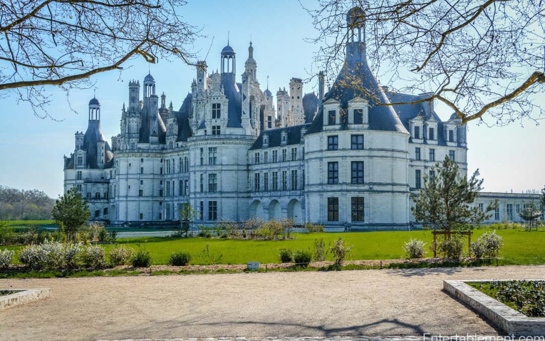 Château de Chambord’s elaborate Renaissance roofline seen from the gardens, framed by early spring foliage.