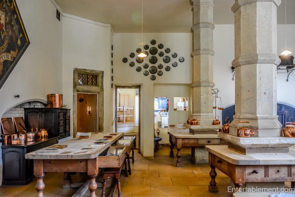 Restored Victorian kitchen at Hardwick Hall featuring a large hearth, copper pots, and traditional cooking implements.
