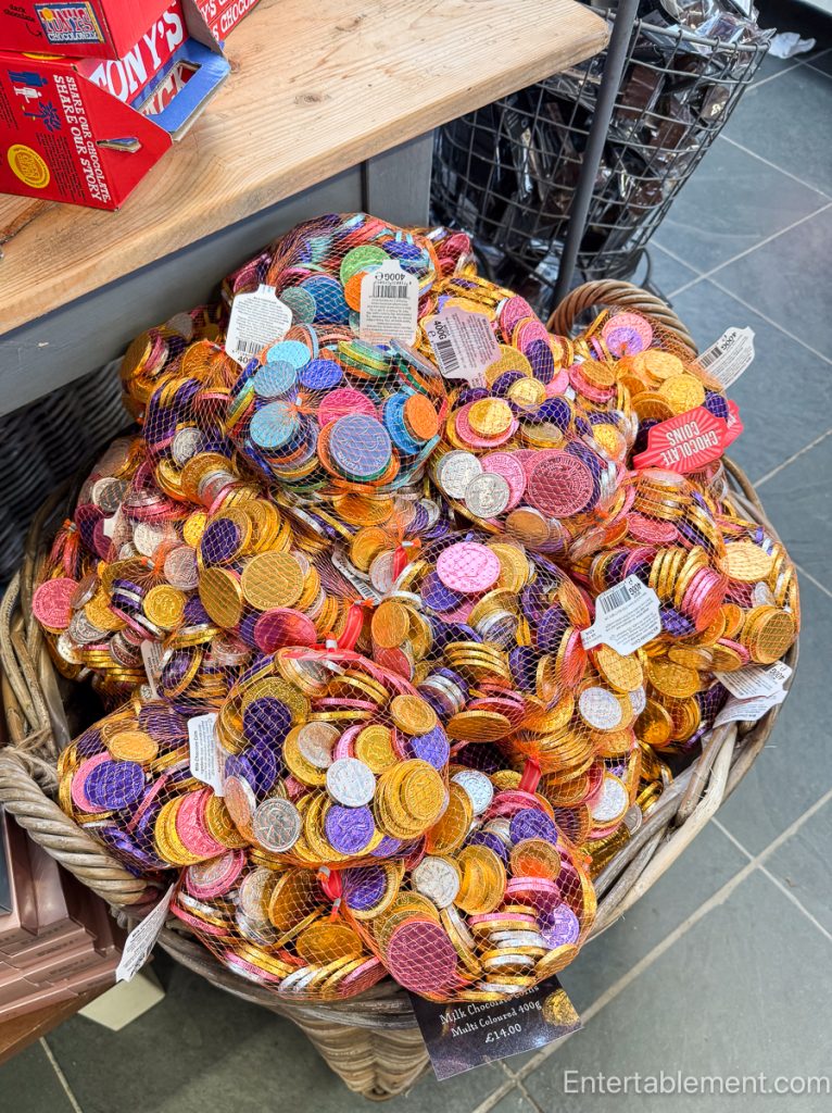 Large basket filled with multi-coloured chocolate coins in net bags.