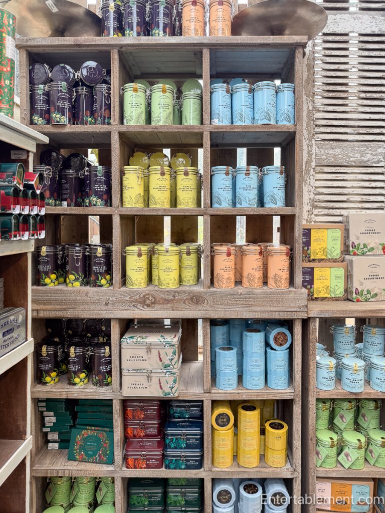 Colourful tins of biscuits, candies, and gourmet treats stacked in cubby shelves.