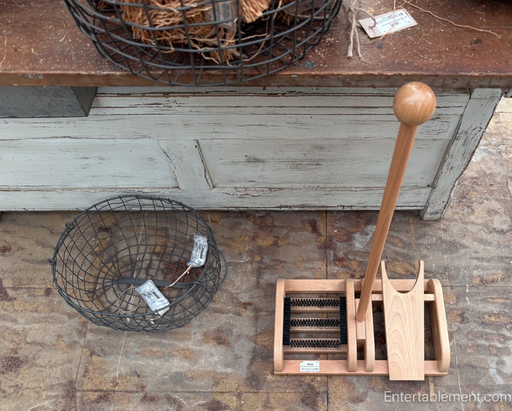 Wooden boot scraper with brushes and wire basket nearby.