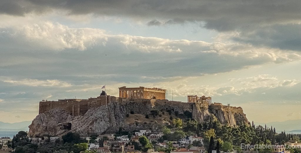 View of the Acropolis in Athens rising above the city, capturing Parthenon and classical ruins against a blue sky.