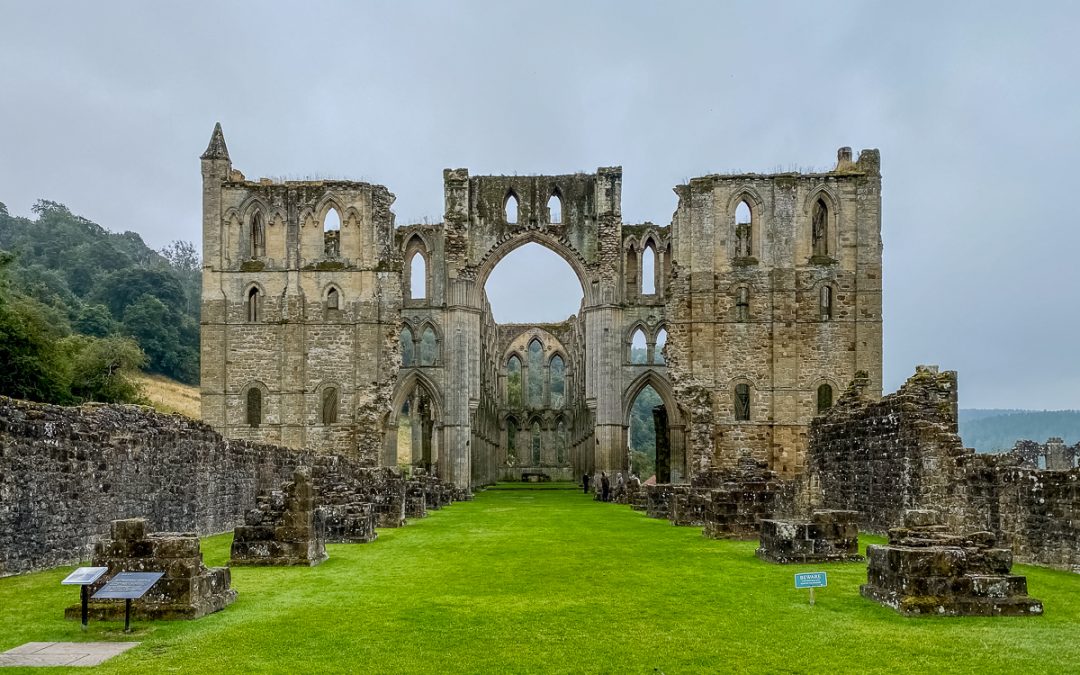 West front of Rievaulx Abbey showing the remains of twin towers and the large central arch opening into the nave.