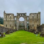 West front of Rievaulx Abbey showing the remains of twin towers and the large central arch opening into the nave.