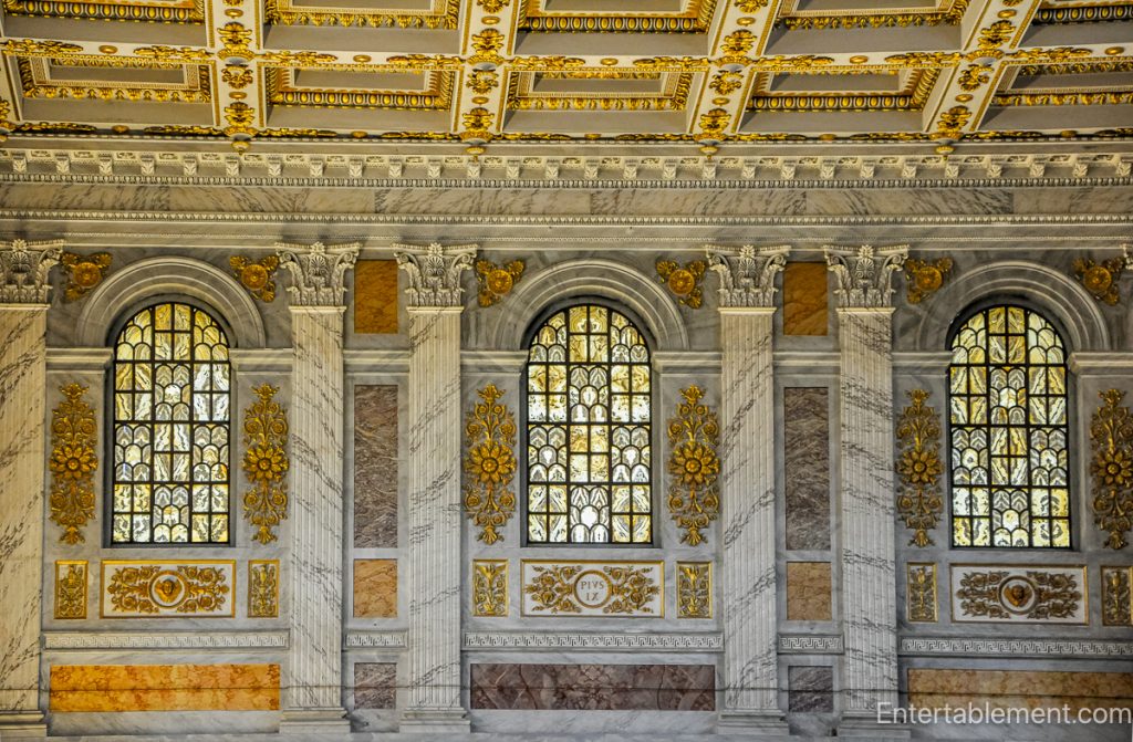 Detail of marble-clad walls and arched windows inside Santa Maria Maggiore, decorated with gold and classical motifs.