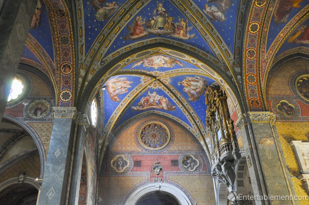 Painted blue vaulted ceiling with gold stars, angels, and decorative patterns inside Santa Maria sopra Minerva in Rome.