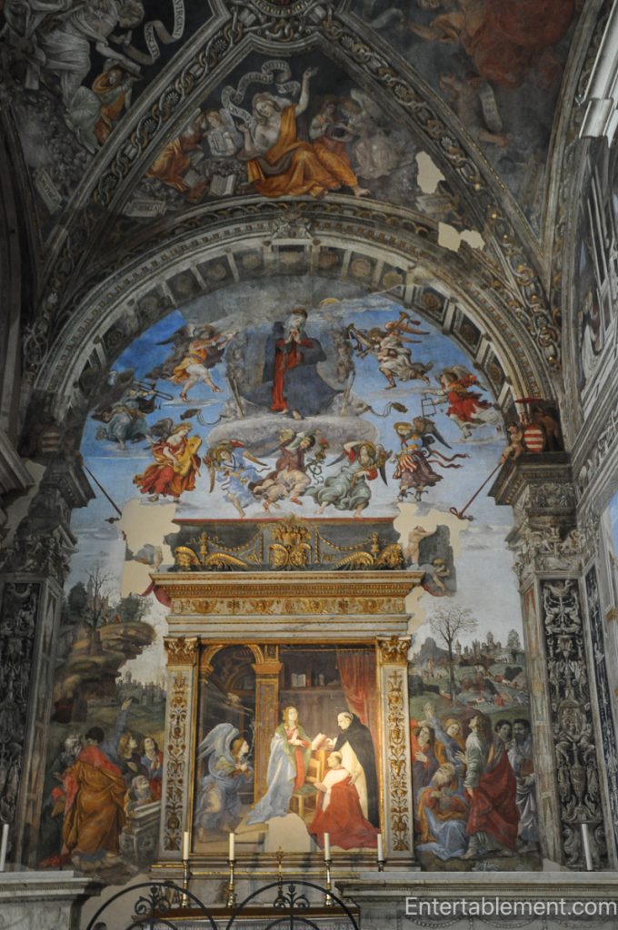 Frescoed chapel interior with illusionistic architecture and religious scenes inside Santa Maria in Trastevere, Rome.
