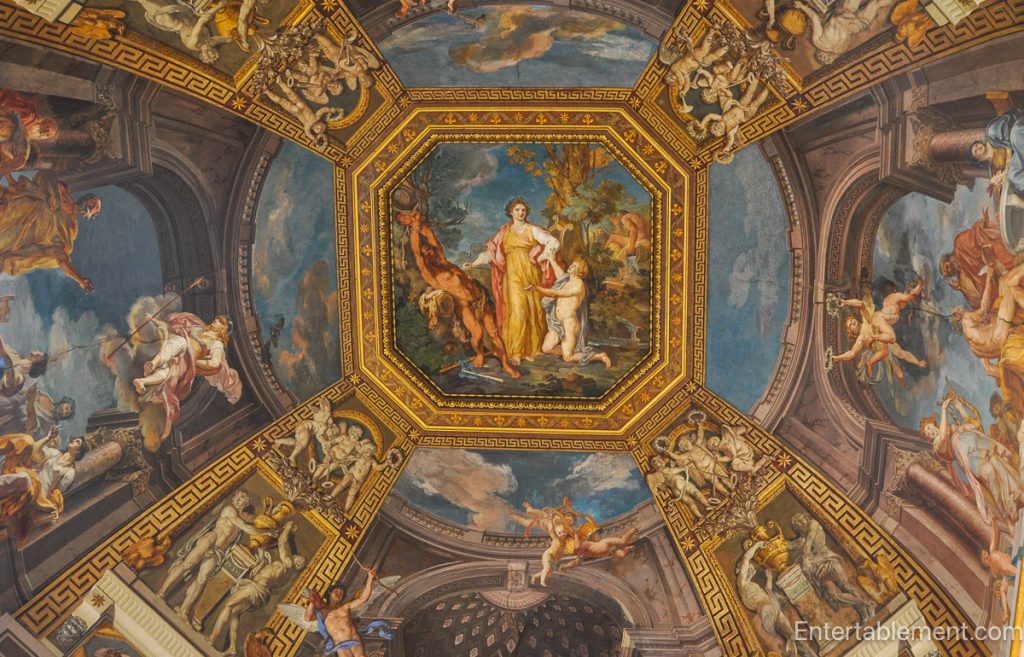 Octagonal ceiling fresco depicting mythological figures surrounded by ornate architectural frames inside Palazzo Farnese, Rome.