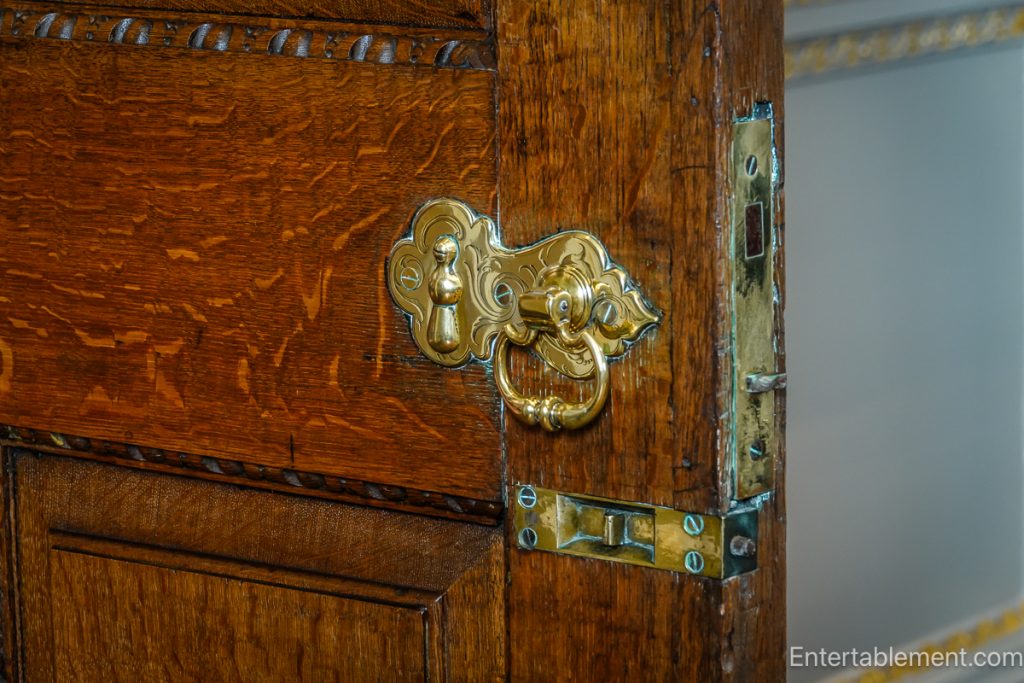 Antique brass latch and handle on panelled wooden door showing age and craftsmanship