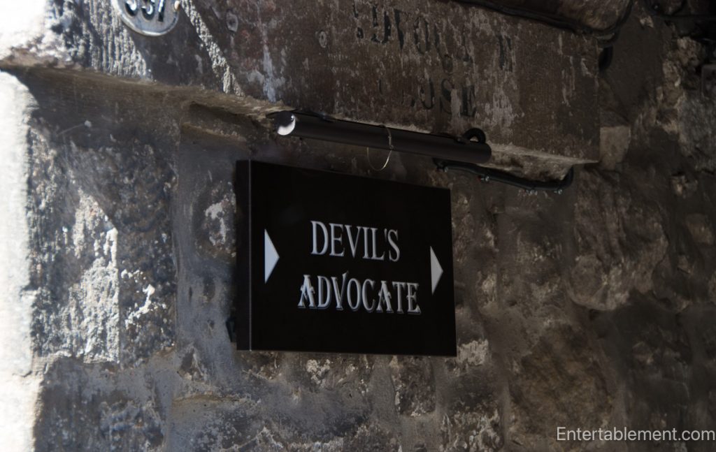 Black Devil’s Advocate sign mounted on the weathered stone wall of an Edinburgh Old Town close