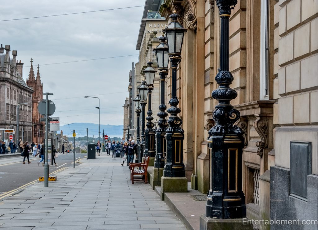 Broad Edinburgh New Town pavement lined with ornate black lampposts and classical stone buildings